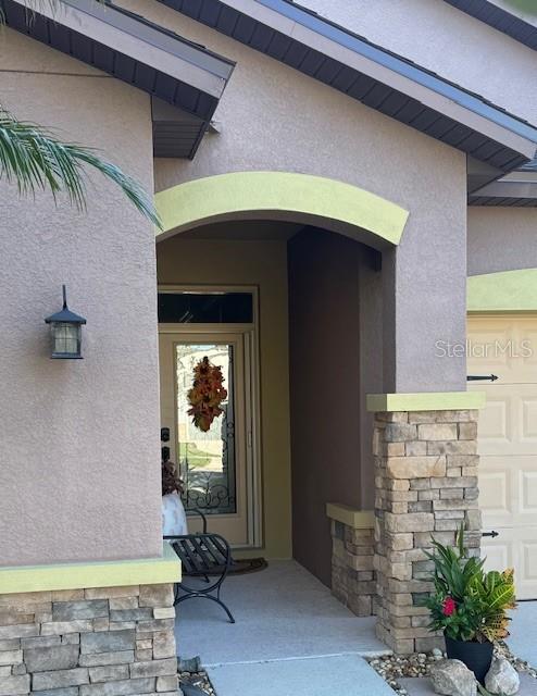 entrance to property featuring stone siding and stucco siding