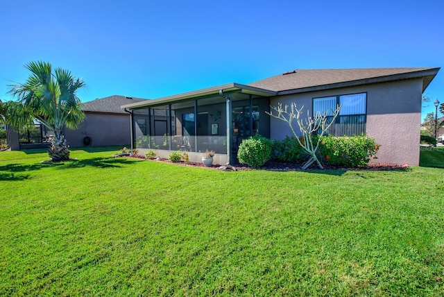 back of property featuring stucco siding, a lawn, and a sunroom