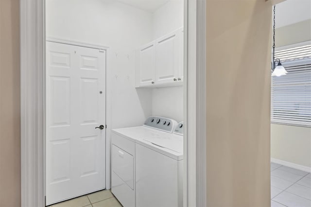 laundry room featuring washer and clothes dryer, cabinets, and light tile patterned floors