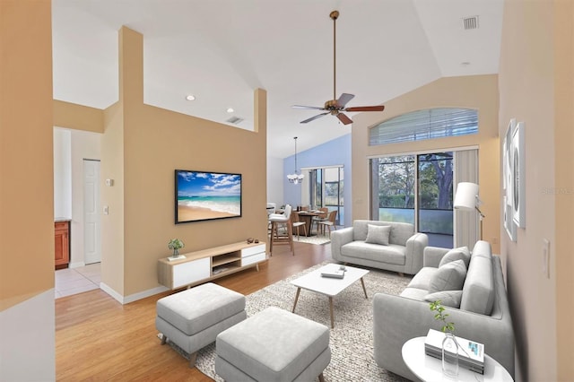 living room featuring ceiling fan with notable chandelier, light wood-type flooring, and high vaulted ceiling