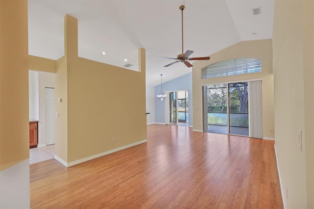 unfurnished living room with ceiling fan with notable chandelier, light hardwood / wood-style floors, and high vaulted ceiling