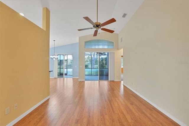 unfurnished living room with high vaulted ceiling, ceiling fan with notable chandelier, and light wood-type flooring