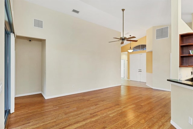 unfurnished living room with high vaulted ceiling, light hardwood / wood-style flooring, and ceiling fan