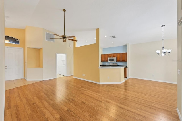 unfurnished living room featuring high vaulted ceiling, light hardwood / wood-style floors, and ceiling fan with notable chandelier