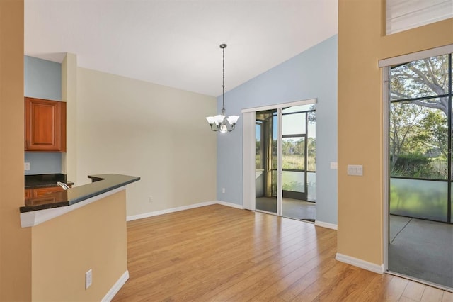 unfurnished dining area with a chandelier, light wood-type flooring, plenty of natural light, and lofted ceiling