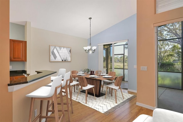 dining space with a chandelier, light hardwood / wood-style floors, and lofted ceiling