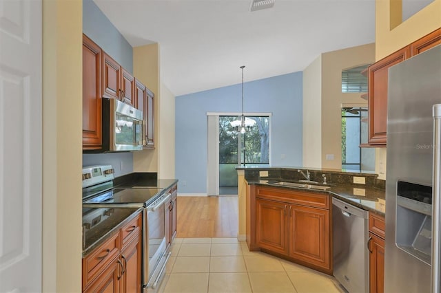 kitchen featuring a chandelier, pendant lighting, lofted ceiling, light tile patterned floors, and appliances with stainless steel finishes