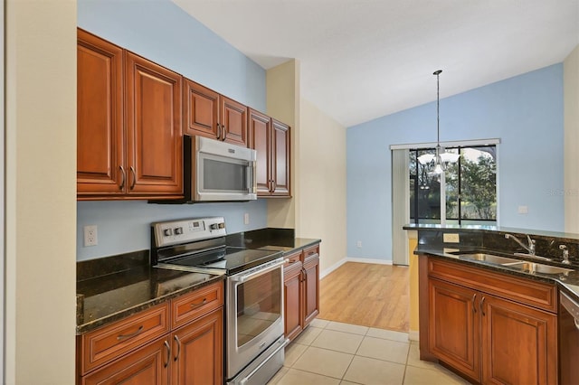 kitchen with stainless steel appliances, vaulted ceiling, sink, light hardwood / wood-style flooring, and hanging light fixtures