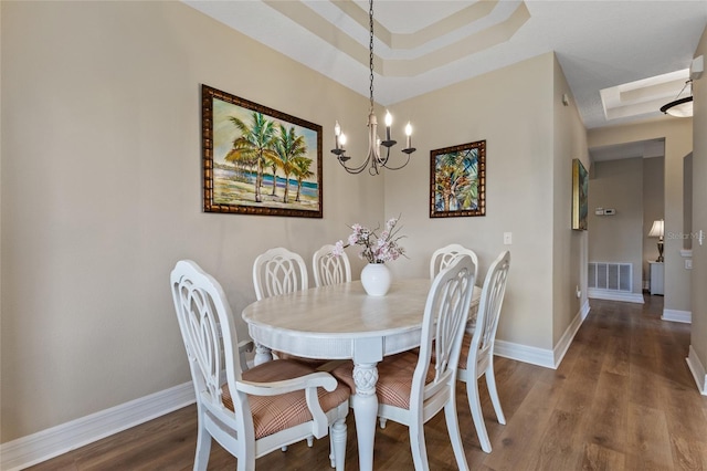 dining area featuring a tray ceiling, hardwood / wood-style floors, and a chandelier