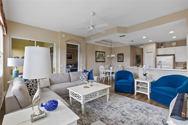 living room featuring dark wood-type flooring and ceiling fan with notable chandelier