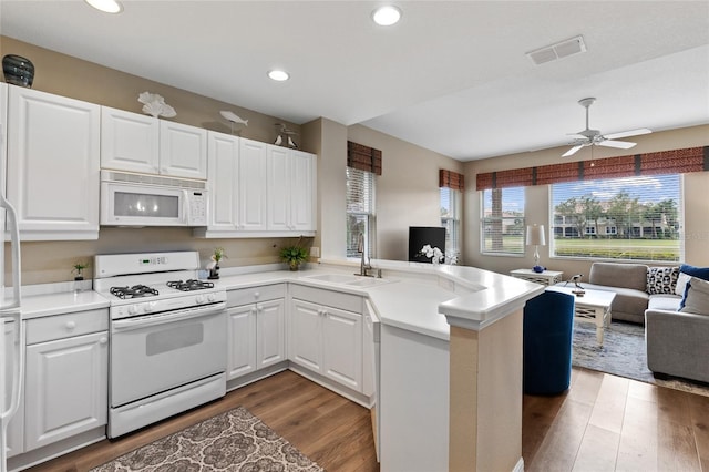 kitchen with white cabinets, sink, white appliances, and kitchen peninsula