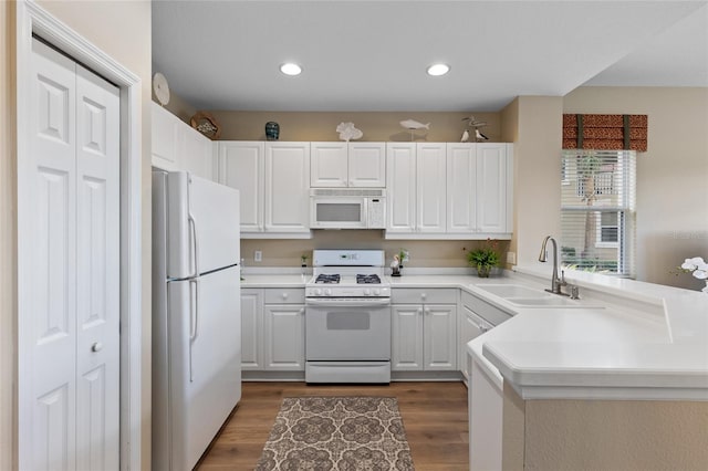 kitchen featuring white appliances, white cabinetry, dark wood-type flooring, and sink