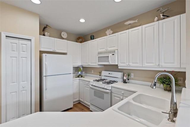 kitchen with white appliances, white cabinetry, dark wood-type flooring, and sink