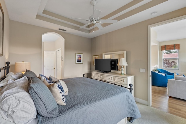 bedroom with a tray ceiling, ceiling fan, and light hardwood / wood-style floors