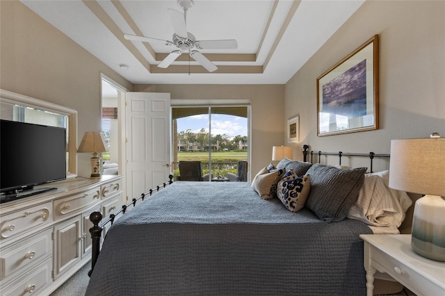 carpeted bedroom with access to outside, a raised ceiling, and ceiling fan