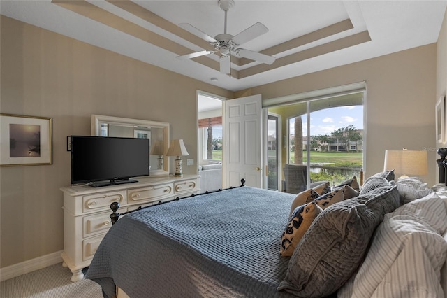 bedroom with ceiling fan, a raised ceiling, carpet floors, and access to outside