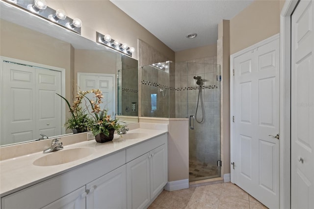 bathroom with tile patterned flooring, vanity, a shower with door, and a textured ceiling