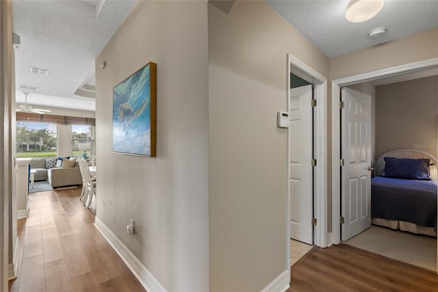 hall featuring light hardwood / wood-style floors and a textured ceiling