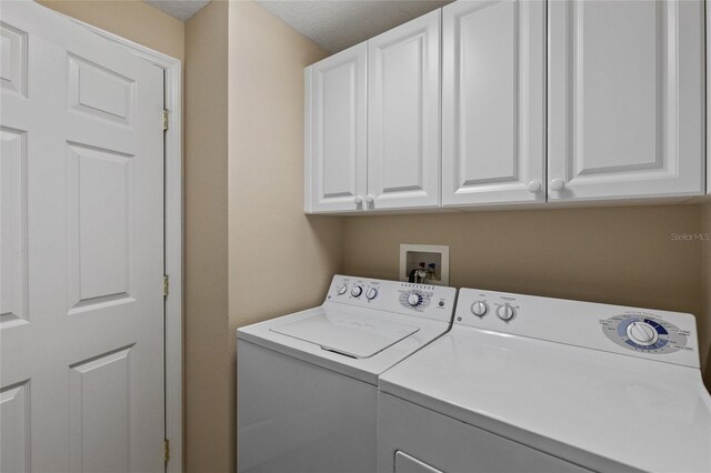 laundry room featuring cabinets, a textured ceiling, and washer and clothes dryer