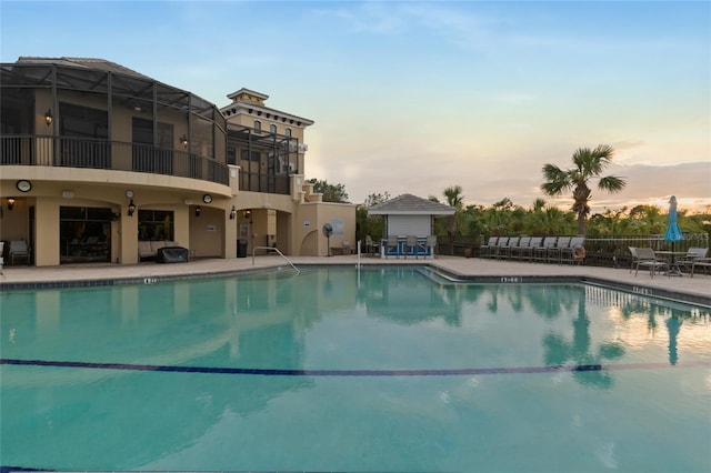 pool at dusk featuring a patio area