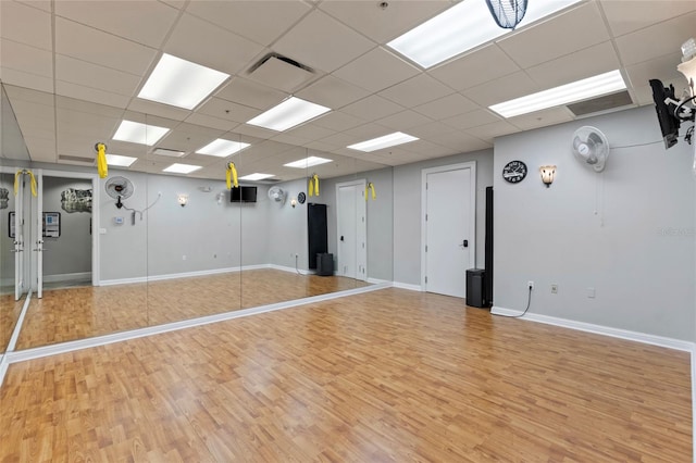 workout room with a paneled ceiling and light hardwood / wood-style floors