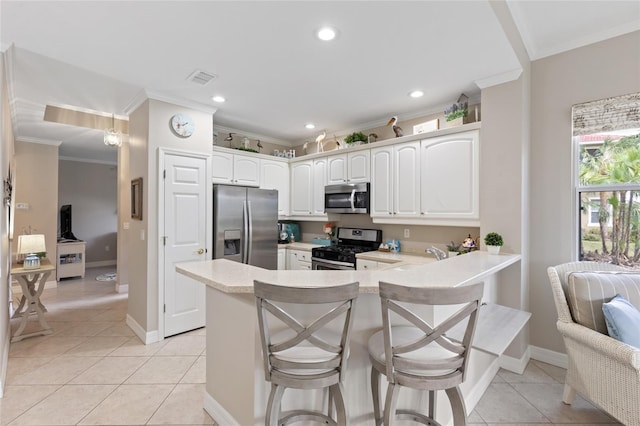 kitchen with white cabinets, crown molding, appliances with stainless steel finishes, kitchen peninsula, and a breakfast bar area