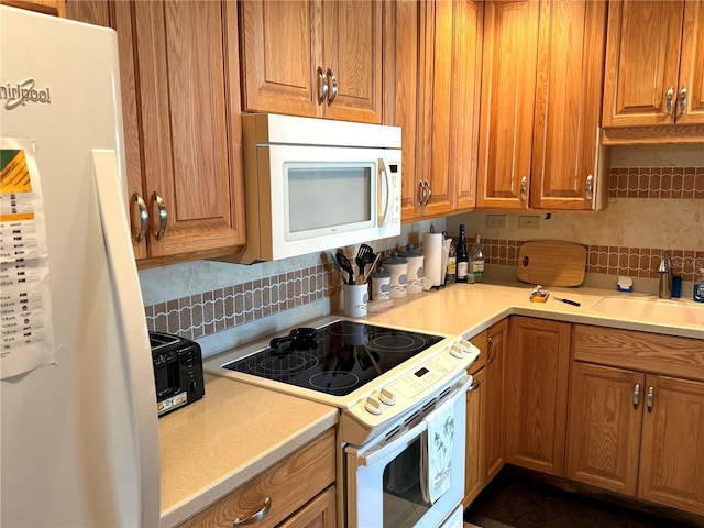 kitchen with backsplash, sink, and white appliances