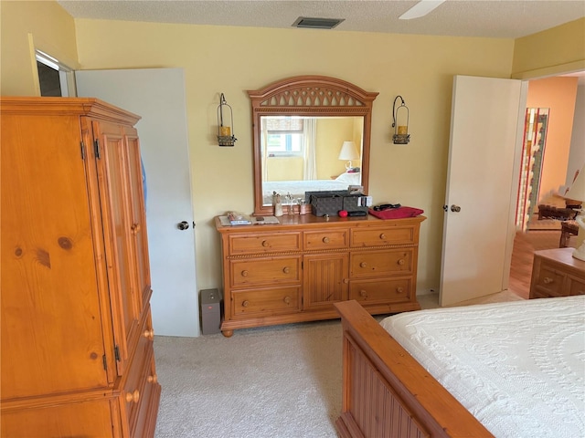 bedroom with a textured ceiling, light colored carpet, and ceiling fan