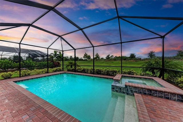 pool at dusk featuring a lanai and an in ground hot tub