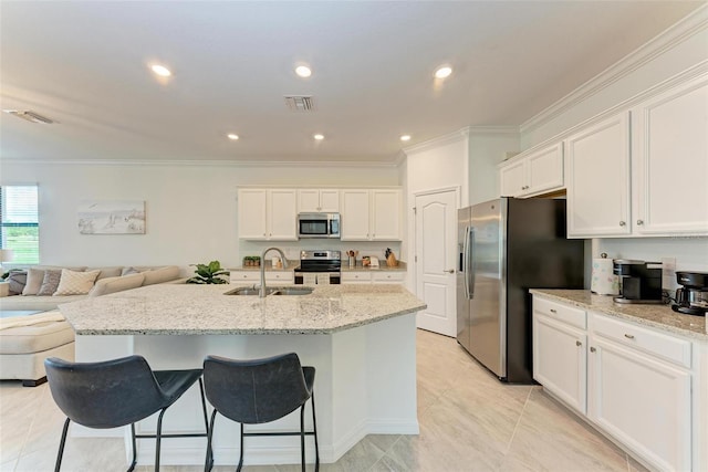 kitchen with sink, light stone countertops, an island with sink, appliances with stainless steel finishes, and white cabinetry