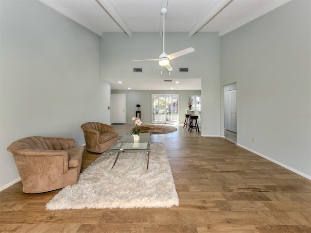 living room with ceiling fan, a high ceiling, wood-type flooring, and beam ceiling