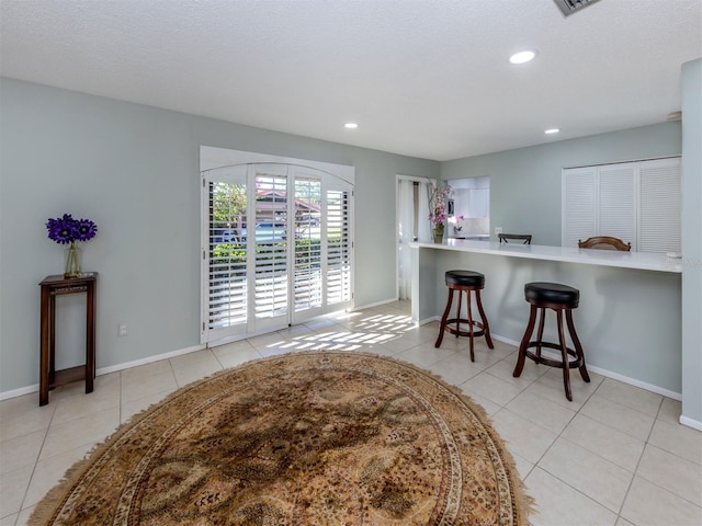 kitchen with a breakfast bar, a textured ceiling, light tile patterned floors, and kitchen peninsula