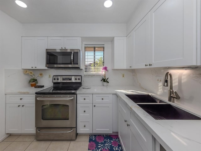 kitchen with appliances with stainless steel finishes, decorative backsplash, white cabinets, and sink