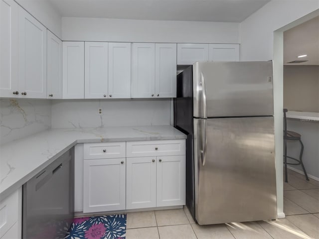 kitchen with light stone countertops, appliances with stainless steel finishes, light tile patterned flooring, and white cabinetry