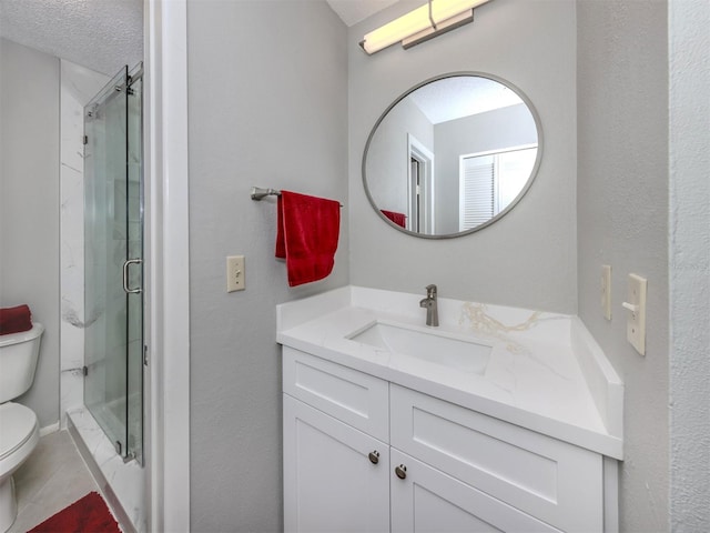 bathroom featuring toilet, vanity, a shower with door, and a textured ceiling