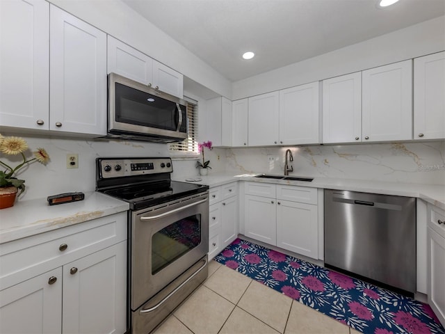 kitchen featuring backsplash, sink, white cabinetry, stainless steel appliances, and light tile patterned floors