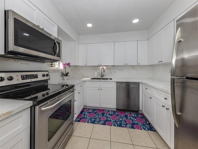 kitchen with white cabinetry, appliances with stainless steel finishes, tasteful backsplash, light stone counters, and sink