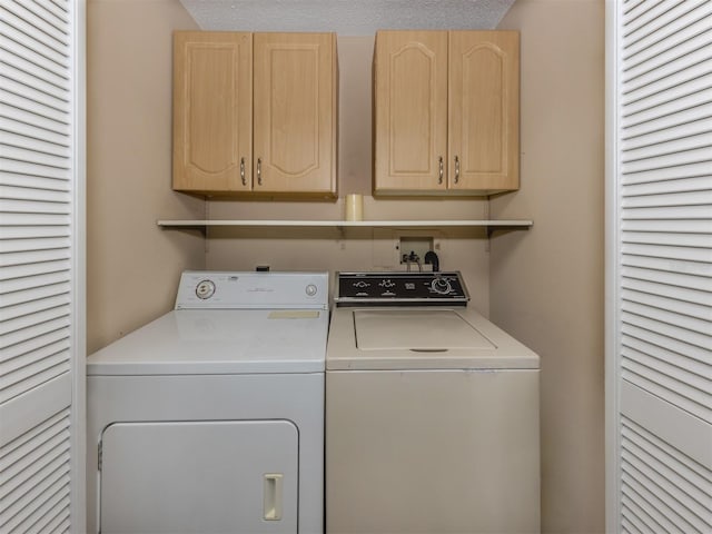 washroom featuring cabinets, a textured ceiling, and washing machine and clothes dryer