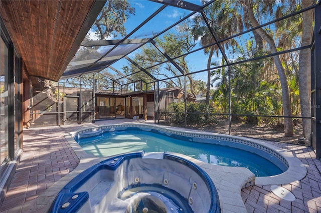 view of pool with a lanai, a patio area, and an in ground hot tub