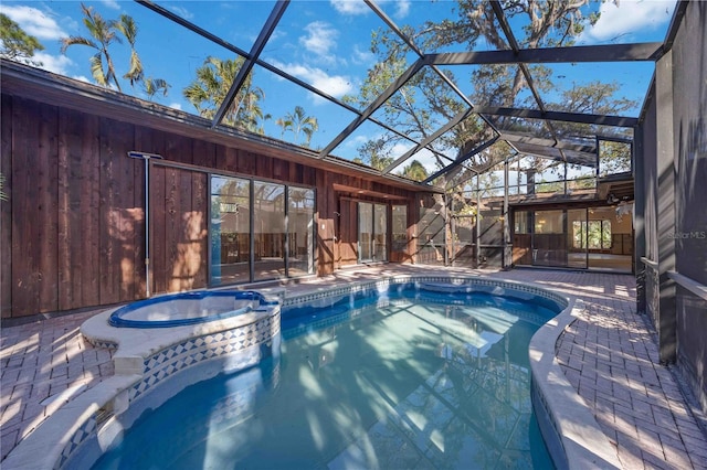 view of pool with glass enclosure, an in ground hot tub, and a patio