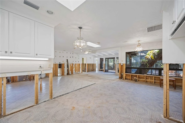 misc room with a chandelier, light tile patterned floors, and a skylight