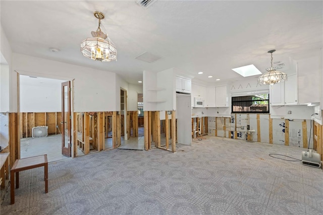 interior space featuring a skylight, carpet floors, and a notable chandelier