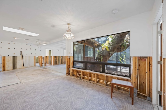 misc room featuring a chandelier, wooden walls, and a skylight