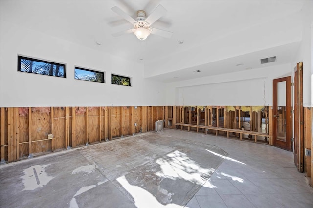 empty room with ceiling fan and wood walls