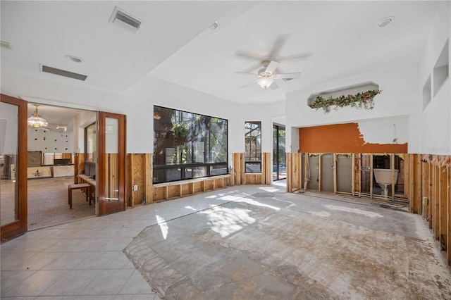 unfurnished living room with light tile patterned floors and ceiling fan with notable chandelier