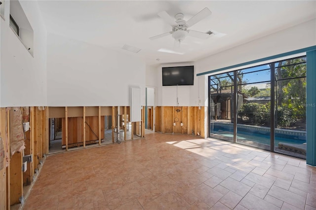 spare room with ceiling fan and wooden walls