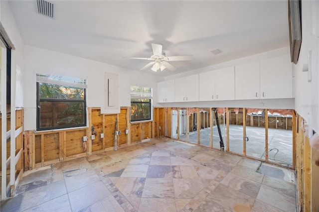 interior space with ceiling fan and wooden walls