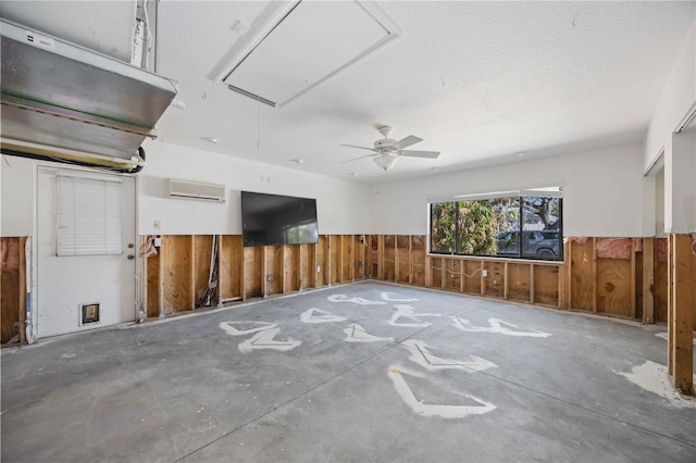 interior space featuring a wall unit AC, wooden walls, ceiling fan, and a textured ceiling