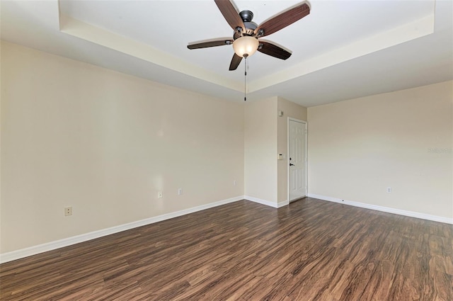 spare room featuring dark hardwood / wood-style floors, ceiling fan, and a tray ceiling