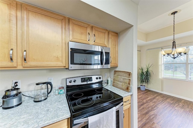1195 Villagio Cir Unit 201, Sarasota, FL 34237 - kitchen with stainless steel appliances, light countertops, a chandelier, wood finished floors, and decorative light fixtures
